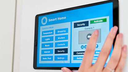 Woman using an application on her digital tablet to control the security and video vigilance of her smart home.